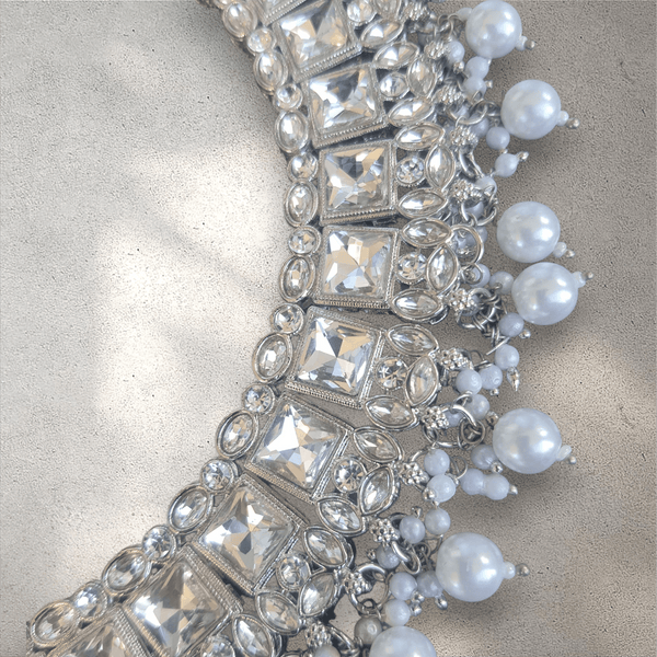 Silver and white beaded jewelry on a textured surface